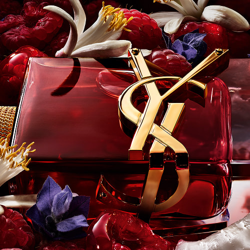 LIBRE Berry Crush red perfume bottle with gold YSL Cassandre logo surrounded by raspberries and flowers.
