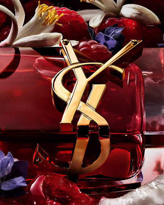 LIBRE Berry Crush red perfume bottle with gold YSL Cassandre logo surrounded by raspberries and flowers, alongside “The new fruity floral fragrance” and a “Discover” button.