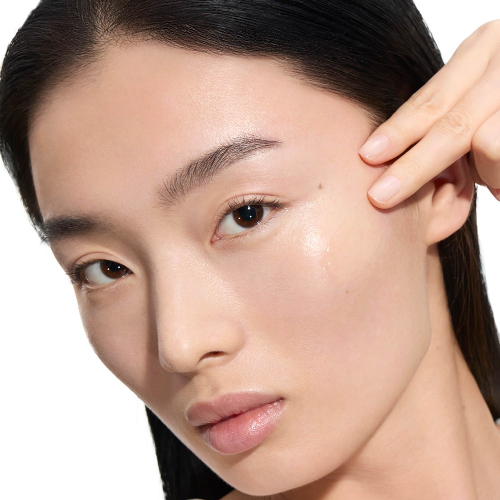 Wen, YSL Beauty model, with fair skin, applying a drop of Pure Shots Youth Reload Serum to her cheek.