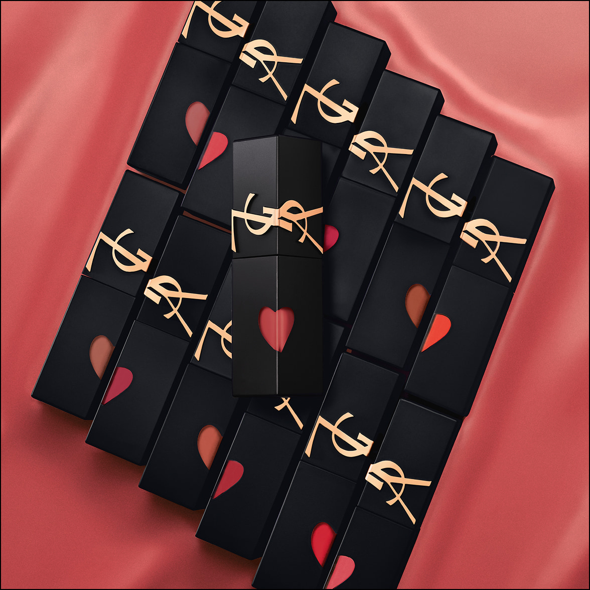 Multiple YSL lipsticks lined up diagonally on a dark background.