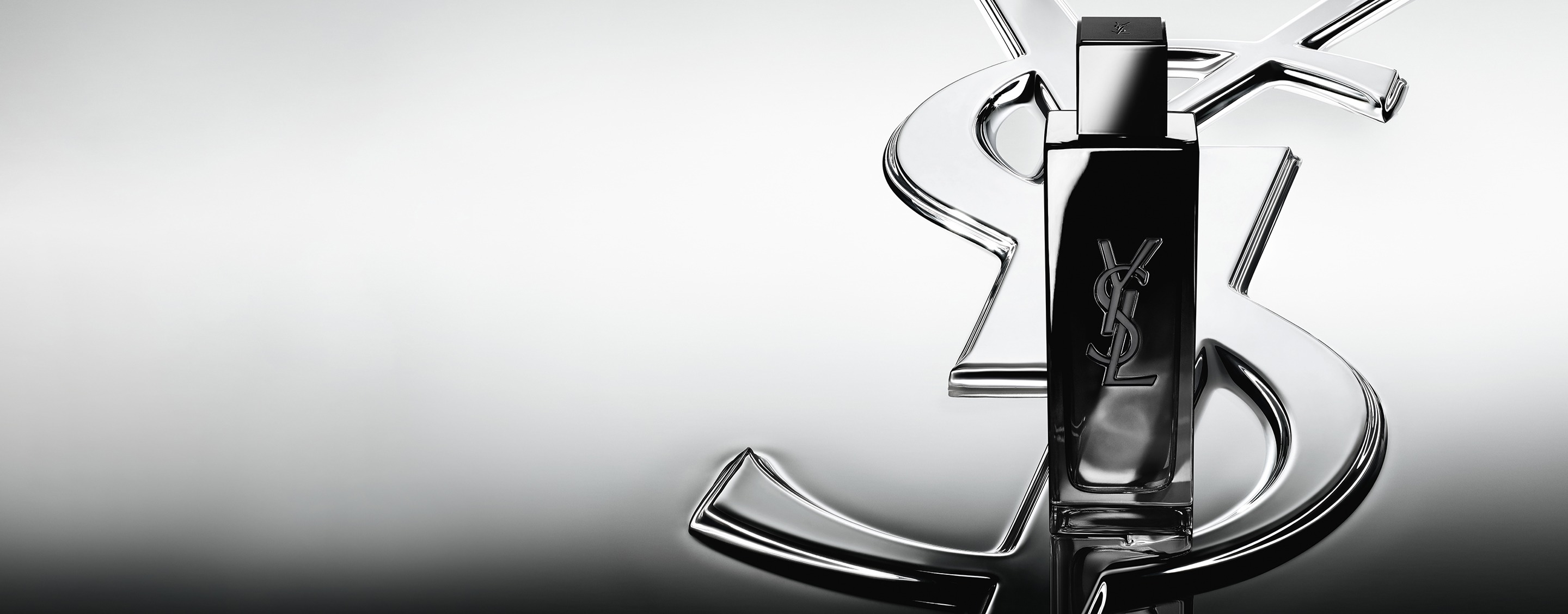 MYSLF Eau de Parfum bottle standing on a large YSL Cassandre logo with a reflective mirror
effect.