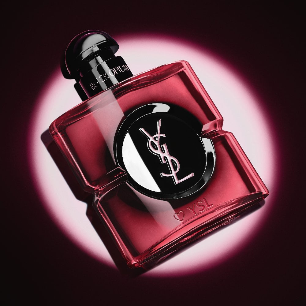 Close-up of the pink lacquered Black Opium Eau de Parfum Pink Glaze bottle with a heart and YSL engraving at the base.